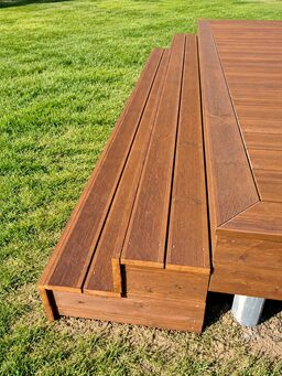 A close-up view of a wooden deck with a grassy background.
